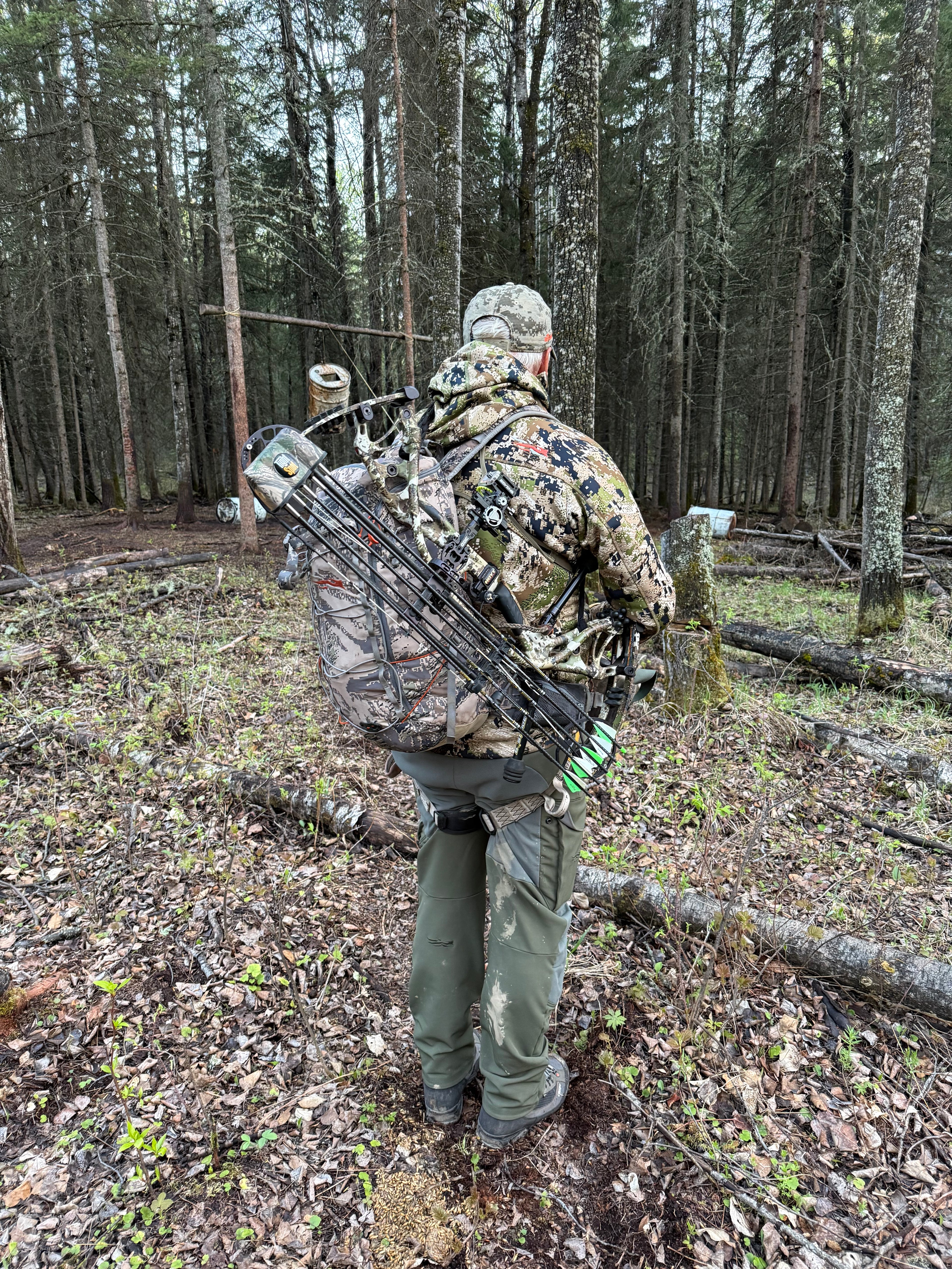 Person in camouflage gear and backpack with a bow secured by Vsling in Canada