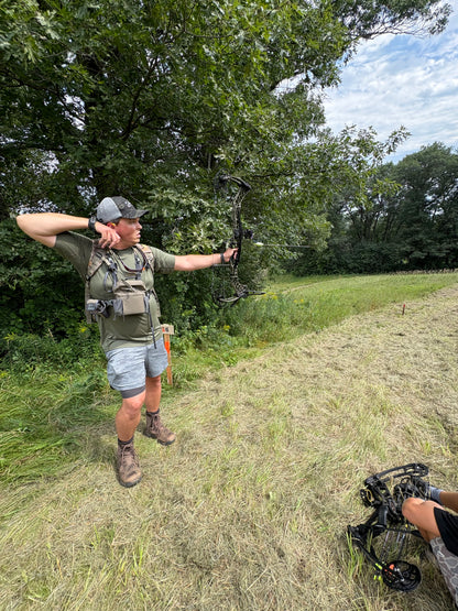 Bowhunter carrying compound bow hands-free with Vsling® bow sling in timber