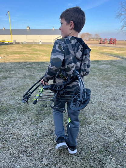 Kid with bow holstered by Vsling Bow Sling going hunting. 