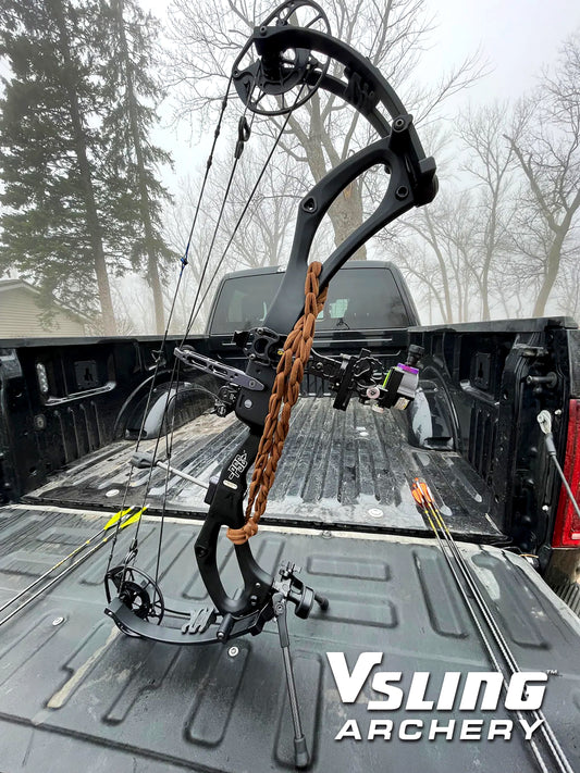 Compound bow on a truck bed with 'Vsling Archery' branding