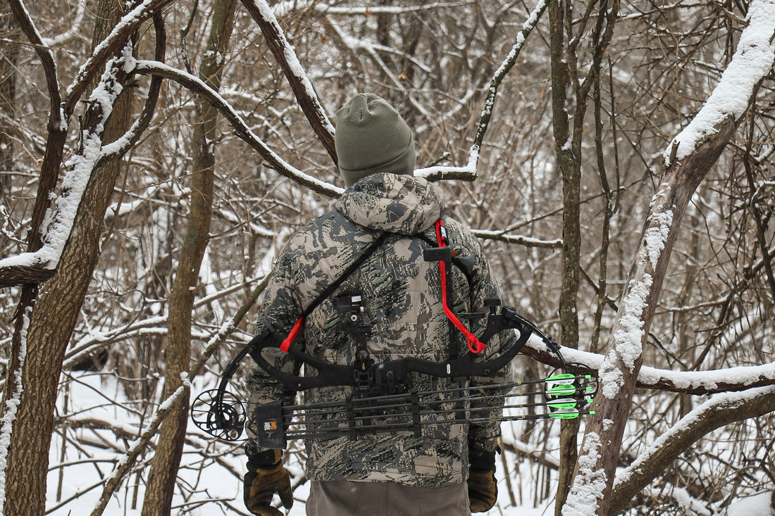 Hunter crossing a fence with Vsling bow sling on a Mathews compound bow in timber.