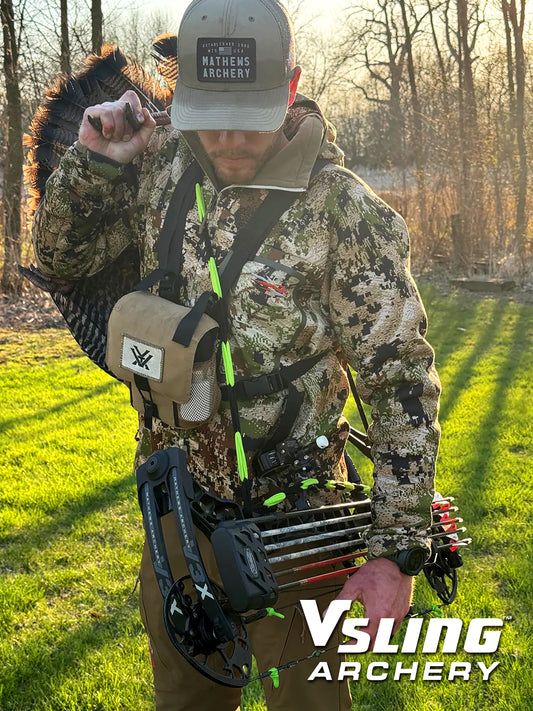 Hunter in camouflage gear holding a turkey with archery equipment, set against a natural background with Vsling Archery watermarking