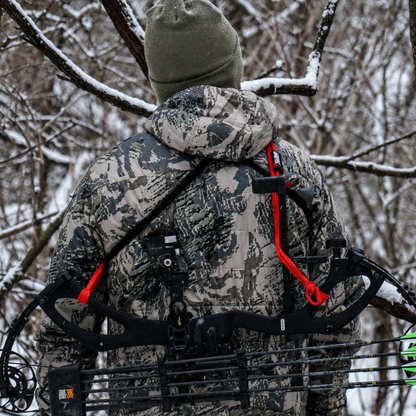 Hunter crossing a fence with Vsling bow sling on a Mathews compound bow in timber.